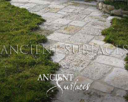 Ancient Surfaces Biblos Limestone flagstones forming a weathered garden path set into wet grass