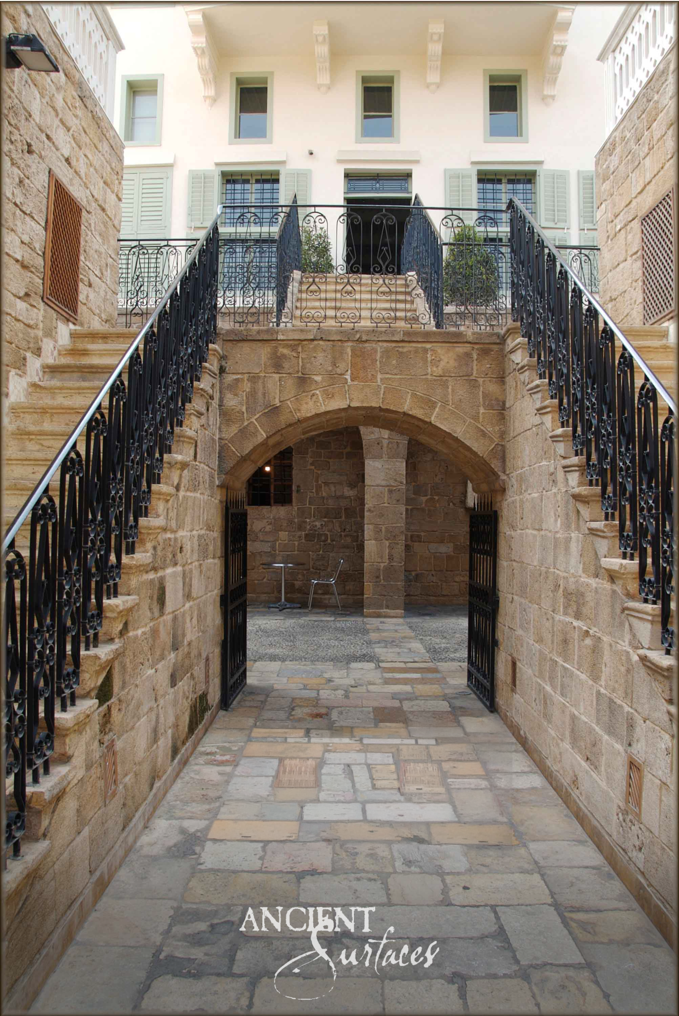 Ancient Surfaces Biblos Limestone courtyard with honey ashlar walls, twin stone stairs and mixed tone paving beneath an arch