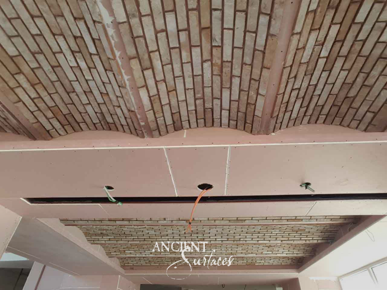 Reclaimed antique brick ceiling vaults from Ancient Surfaces fanning between beams in a room under construction