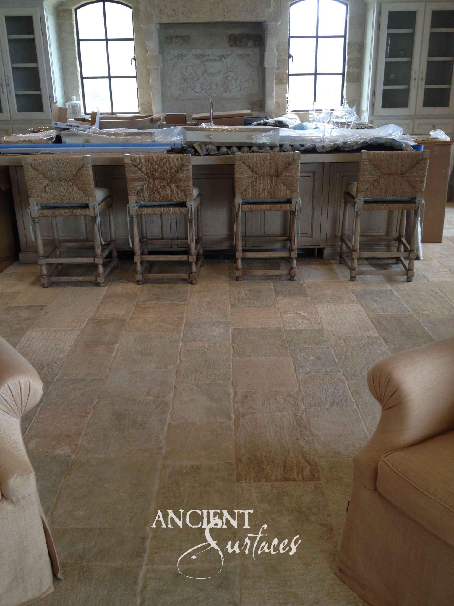 Ancient Surfaces Kronos Limestone flagstone flooring in warm sand tones through a kitchen with a carved stone chimney hood